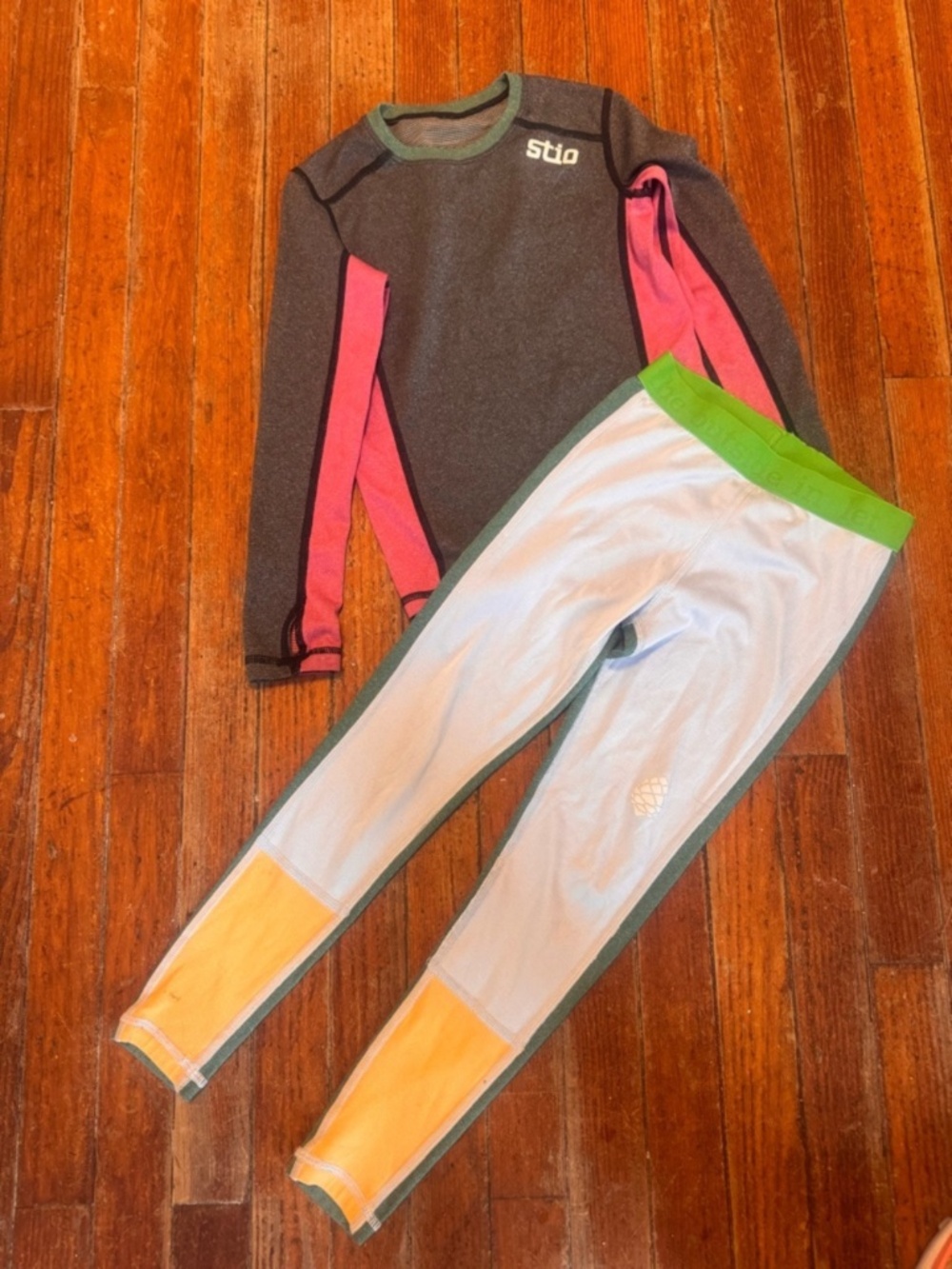 Two-piece Stio kids matching set. Charcoal long-sleeve top with bright pink side